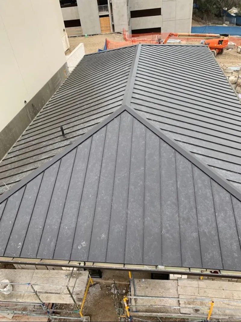 Commercial metal roof construction with crane equipment in Granville